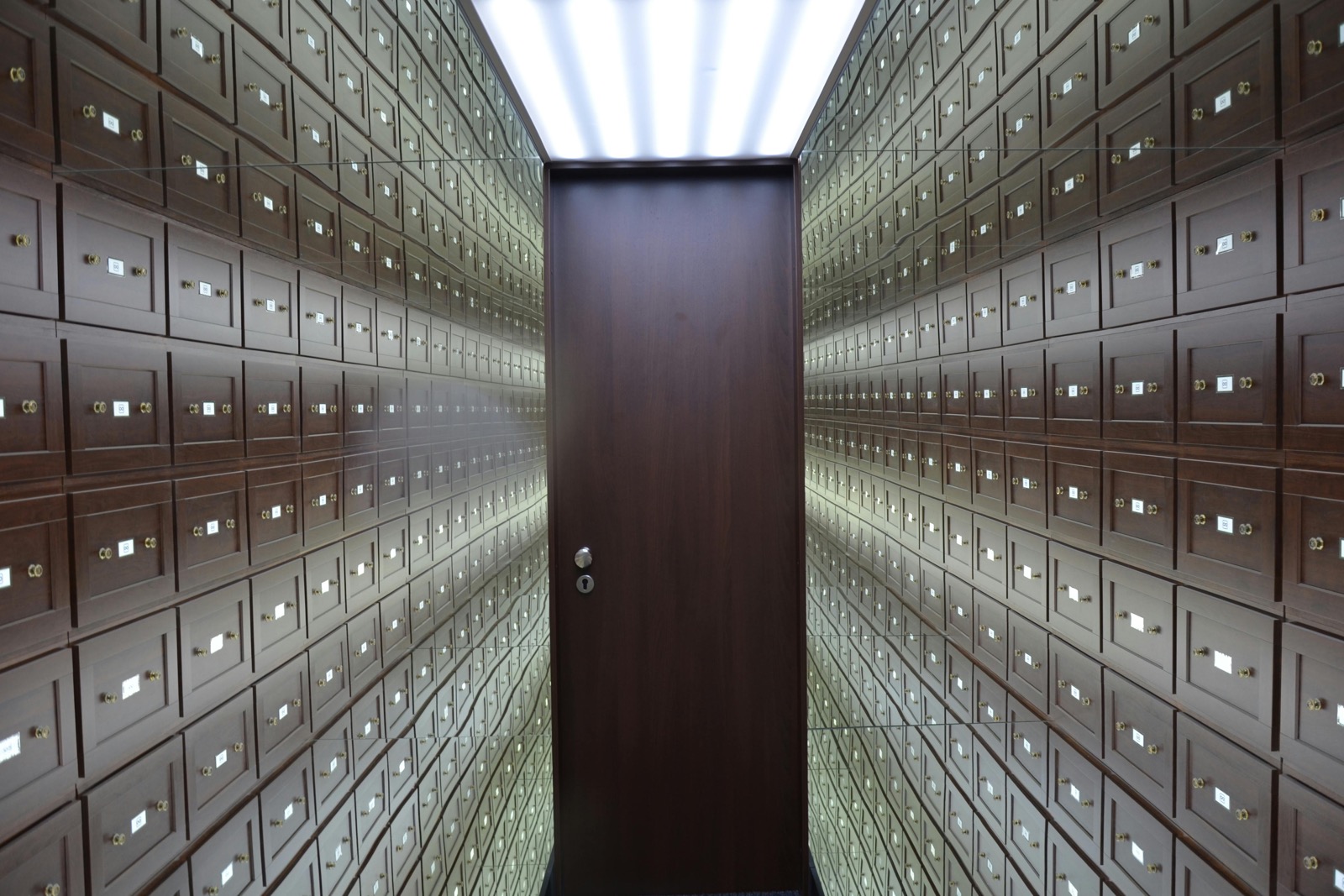 Interior of a modern vault: wooden lockboxes lining the walls with a central wooden door.